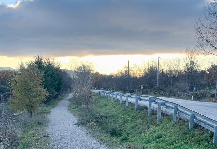 Vista de un camino de tierra que corre paralelo a una carretera asfaltada.